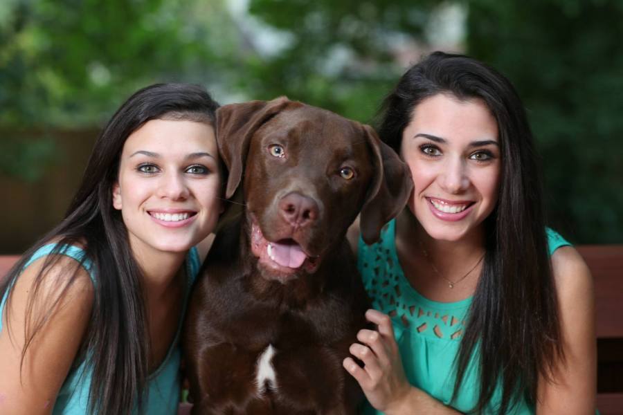 Holly and Kailey pose with their dog Guiness at home 