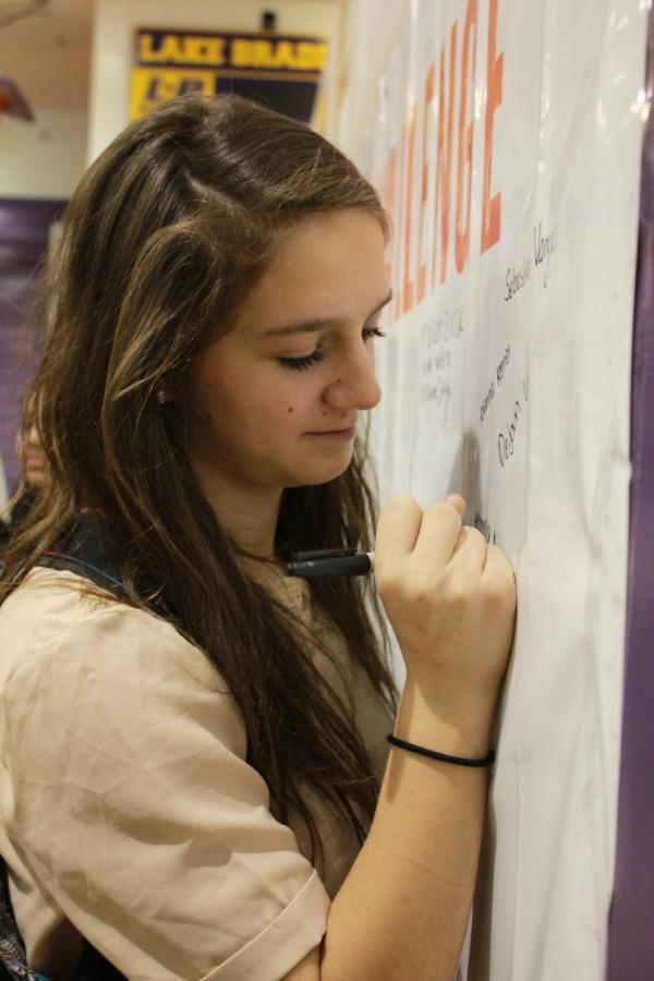 Senior Rianna Renzi accepts Rachel's Challenge by signing her name on the banner after the assembly.